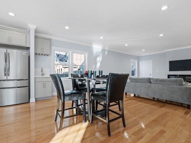 dining space with sink, light hardwood / wood-style flooring, and ornamental molding