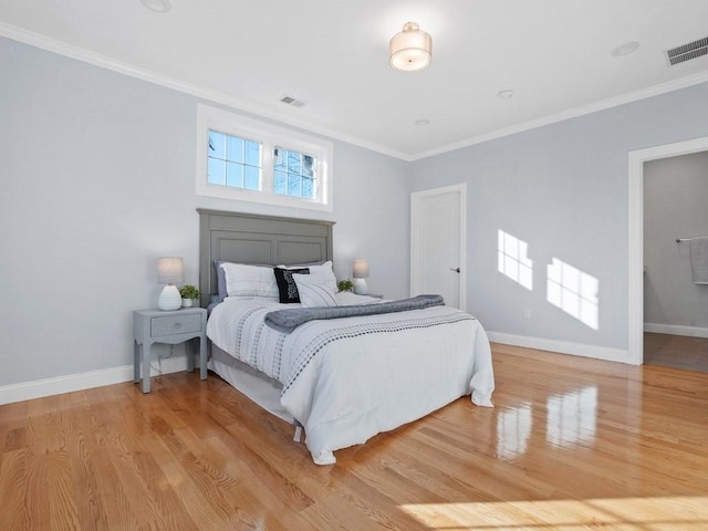 bedroom with ornamental molding and light hardwood / wood-style floors