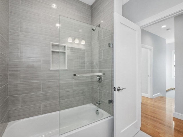 bathroom with tiled shower / bath combo and hardwood / wood-style floors