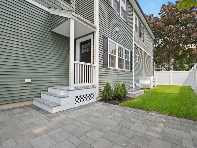 entrance to property featuring a patio area and a yard