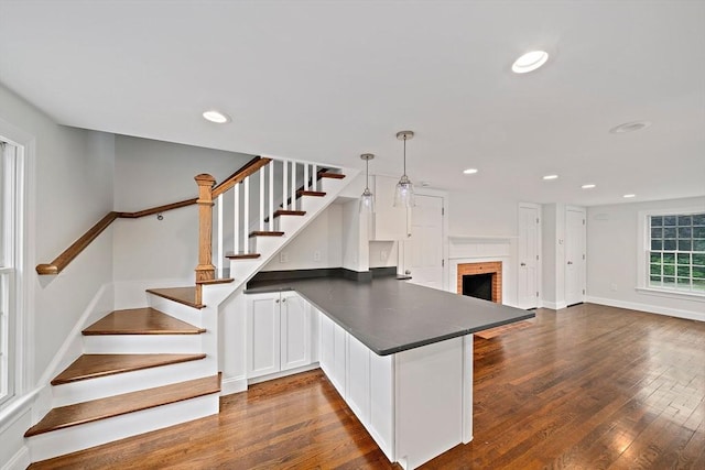 24 Summer St Unit A, Kingston, MA 02364 - kitchen with dark countertops, a peninsula, dark wood finished floors, open floor plan, and open shelves