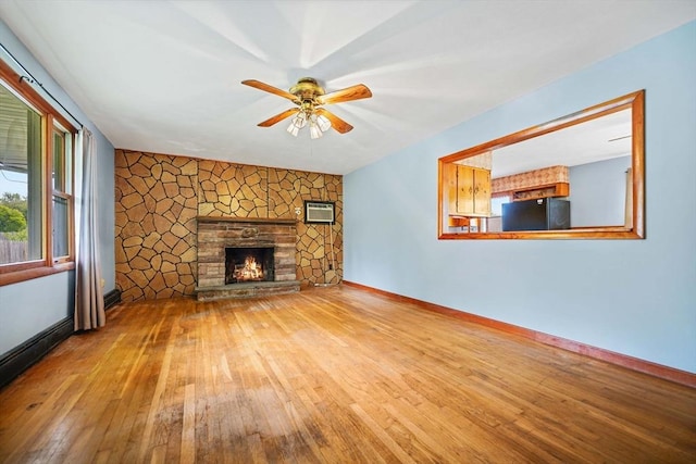 20 Roy St, Fairhaven, MA 02719 - unfurnished living room with a wall unit AC, hardwood / wood-style floors, a ceiling fan, baseboards, and a stone fireplace