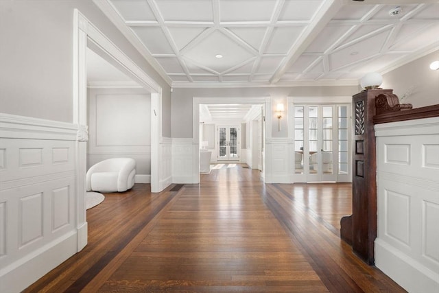 hall featuring a wainscoted wall, dark wood-style flooring, coffered ceiling, french doors, and crown molding