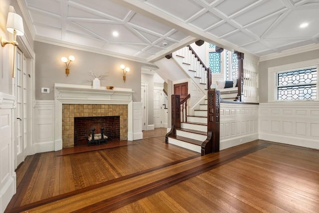 unfurnished living room with plenty of natural light, a fireplace, stairway, and wood-type flooring