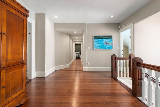 hallway with dark wood-type flooring, recessed lighting, an upstairs landing, and baseboards