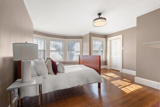 bedroom with crown molding, multiple windows, baseboards, and wood finished floors