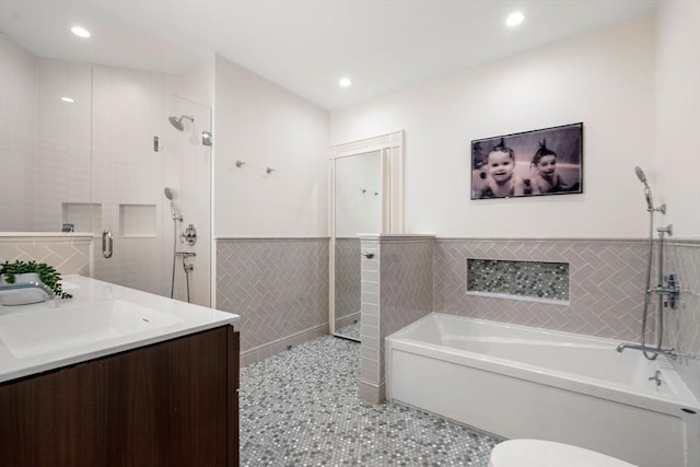 full bath featuring a garden tub, tile walls, a shower stall, vanity, and tile patterned floors