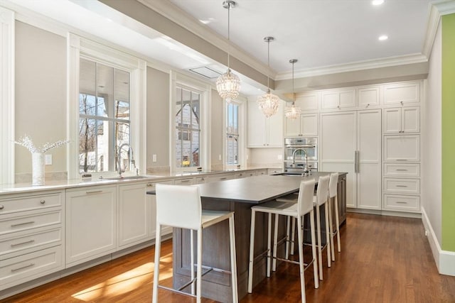 kitchen featuring white cabinets, a sink, oven, and a center island