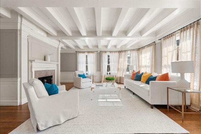 living area with dark wood-style floors, a tile fireplace, beamed ceiling, and a decorative wall