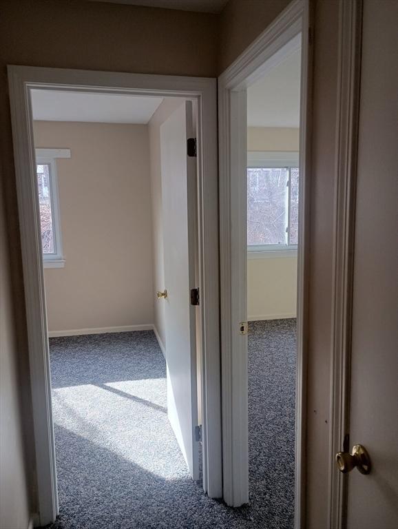 hallway featuring carpet flooring and baseboards