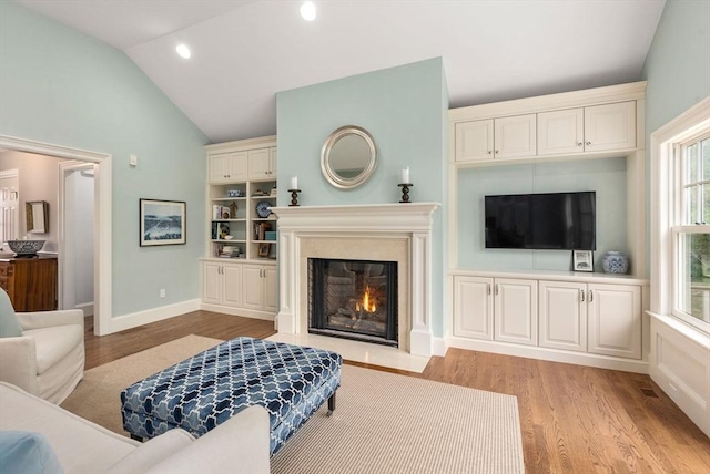 living room with a fireplace with flush hearth, light wood-type flooring, vaulted ceiling, baseboards, and recessed lighting