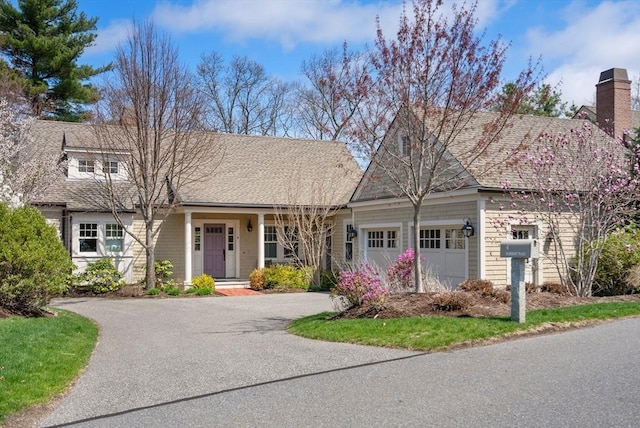 view of front of house featuring a porch, a shingled roof, aphalt driveway, and a garage