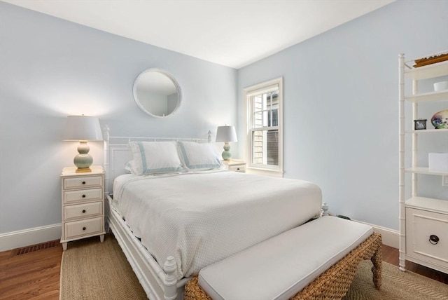 bedroom with visible vents, baseboards, and wood finished floors