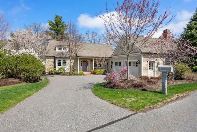 view of front of home featuring a chimney, an attached garage, and aphalt driveway
