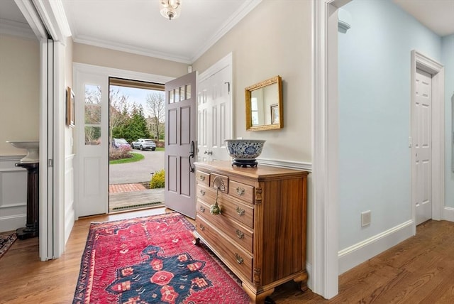 entryway featuring arched walkways, crown molding, and light wood-style flooring