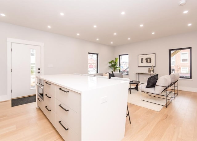 kitchen featuring light wood-style floors, modern cabinets, a kitchen island, and white cabinetry