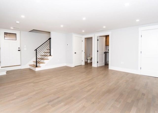 unfurnished living room with light wood-type flooring, recessed lighting, baseboards, and stairway
