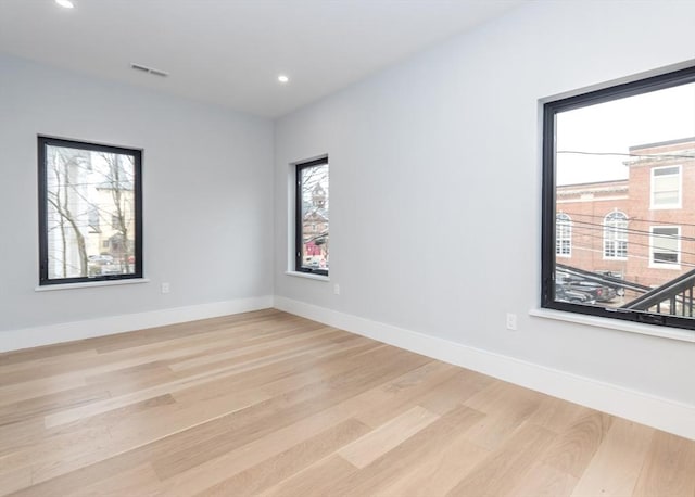 empty room with light wood-style floors, baseboards, recessed lighting, and visible vents