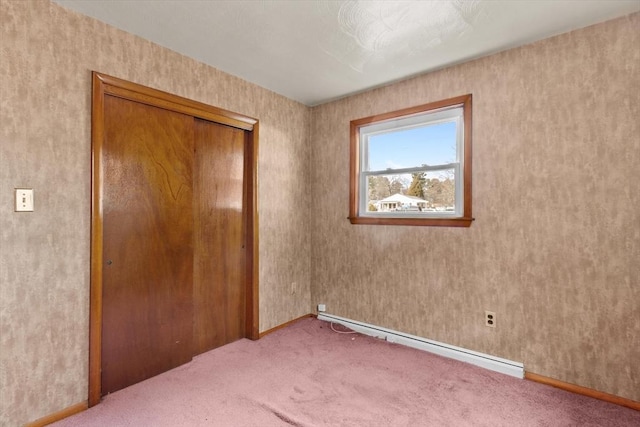 unfurnished bedroom featuring a closet, carpet flooring, a baseboard heating unit, and baseboards