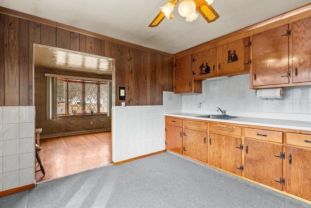 kitchen with a sink, ceiling fan, brown cabinetry, and light countertops