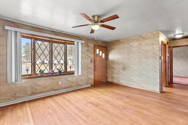 empty room featuring a ceiling fan, wood finished floors, baseboards, and baseboard heating