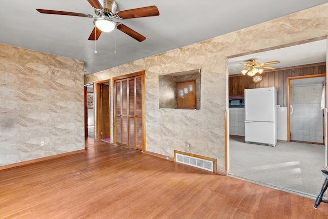 unfurnished room featuring visible vents, baseboards, a ceiling fan, and wood finished floors