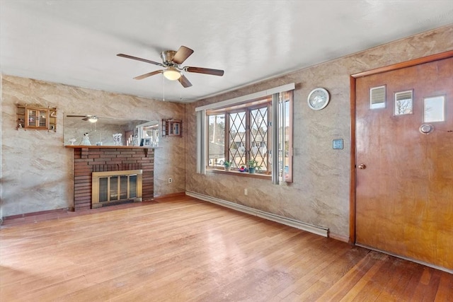 unfurnished living room featuring baseboards, a fireplace, wood finished floors, and a ceiling fan