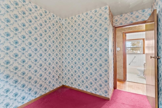 spare room with wallpapered walls and baseboards