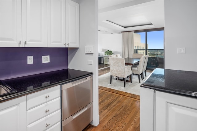 kitchen featuring dark stone counters, white cabinets, hardwood / wood-style flooring, and stainless steel dishwasher