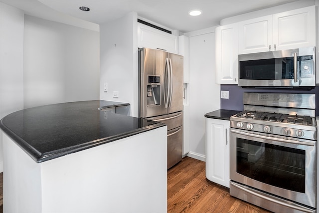 kitchen with wood-type flooring, white cabinets, stainless steel appliances, and kitchen peninsula