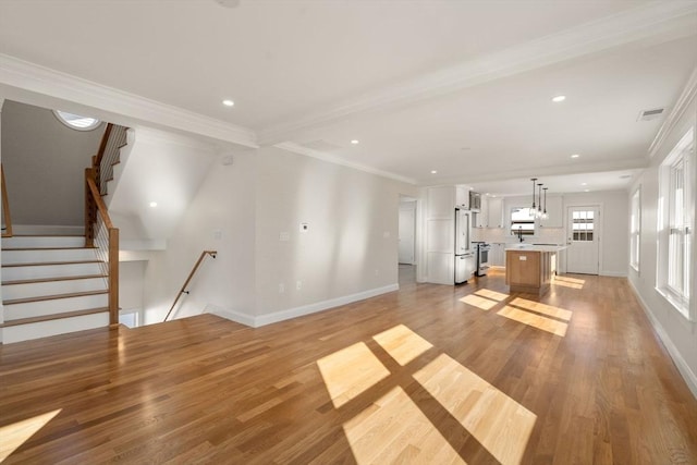 unfurnished living room featuring ornamental molding and light hardwood / wood-style flooring