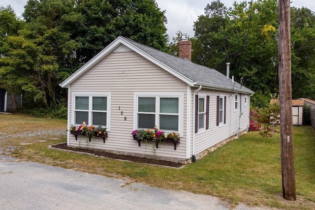 view of front of house with a front lawn and a storage shed