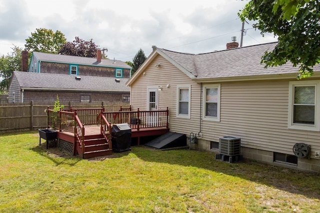 rear view of house featuring a wooden deck, cooling unit, and a lawn