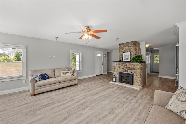 living room featuring light wood-type flooring, a fireplace, and ceiling fan