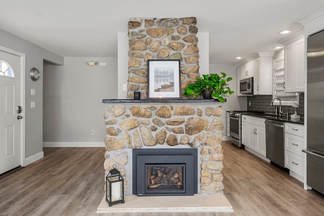 kitchen with appliances with stainless steel finishes, white cabinetry, light hardwood / wood-style floors, and tasteful backsplash