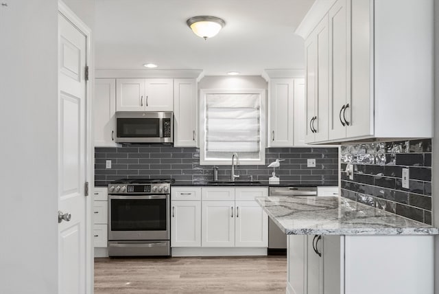 kitchen featuring light hardwood / wood-style floors, appliances with stainless steel finishes, sink, and white cabinetry