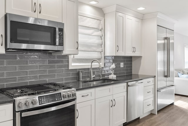 kitchen with decorative backsplash, dark hardwood / wood-style floors, sink, white cabinetry, and appliances with stainless steel finishes