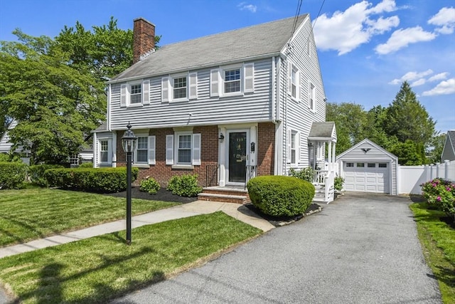 223 Warren St, Waltham, MA 02453 - view of front of home with a chimney, brick siding, a garage, an outdoor structure, and driveway