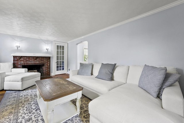 223 Warren St, Waltham, MA 02453 - living area featuring crown molding, wood finished floors, a fireplace, arched walkways, and a textured ceiling