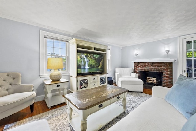 223 Warren St, Waltham, MA 02453 - living room with wood finished floors, a brick fireplace, a textured ceiling, baseboards, and crown molding