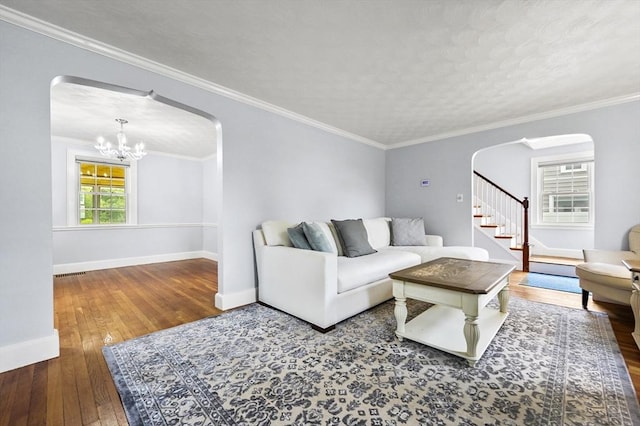 223 Warren St, Waltham, MA 02453 - living room featuring arched walkways, hardwood / wood-style flooring, a chandelier, baseboards, and ornamental molding