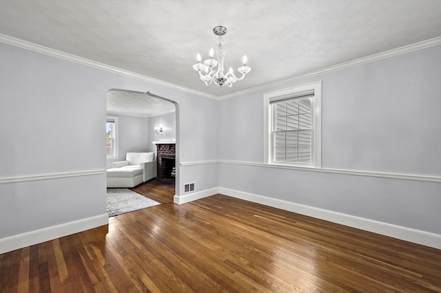 223 Warren St, Waltham, MA 02453 - unfurnished dining area with arched walkways, a brick fireplace, baseboards, wood-type flooring, and ornamental molding