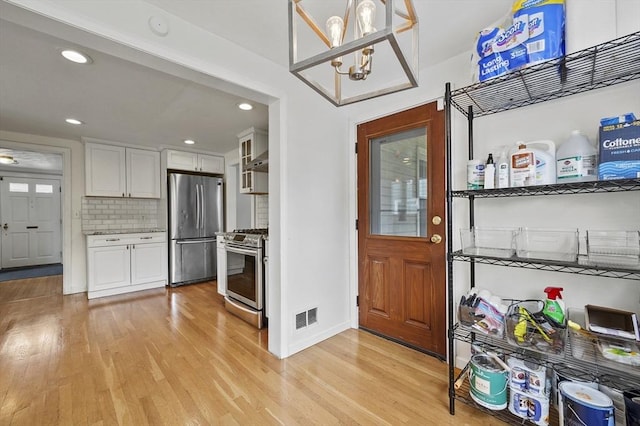 223 Warren St, Waltham, MA 02453 - kitchen featuring appliances with stainless steel finishes, light wood-style floors, white cabinetry, tasteful backsplash, and recessed lighting
