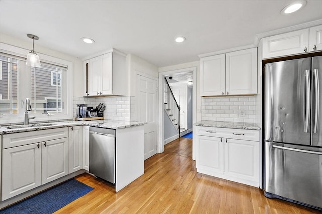 223 Warren St, Waltham, MA 02453 - kitchen featuring appliances with stainless steel finishes, a sink, white cabinets, light wood-type flooring, and recessed lighting
