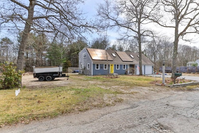 view of front of home featuring roof mounted solar panels, an attached garage, and driveway