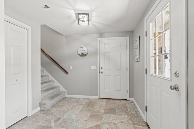 entrance foyer featuring stairway, stone finish flooring, baseboards, and a wealth of natural light