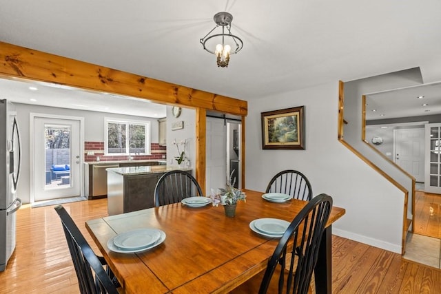 dining room featuring light wood finished floors, baseboards, and a barn door
