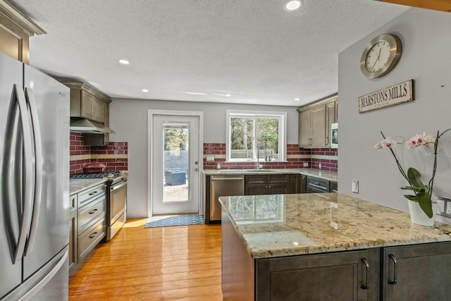 kitchen featuring backsplash, a textured ceiling, appliances with stainless steel finishes, and under cabinet range hood