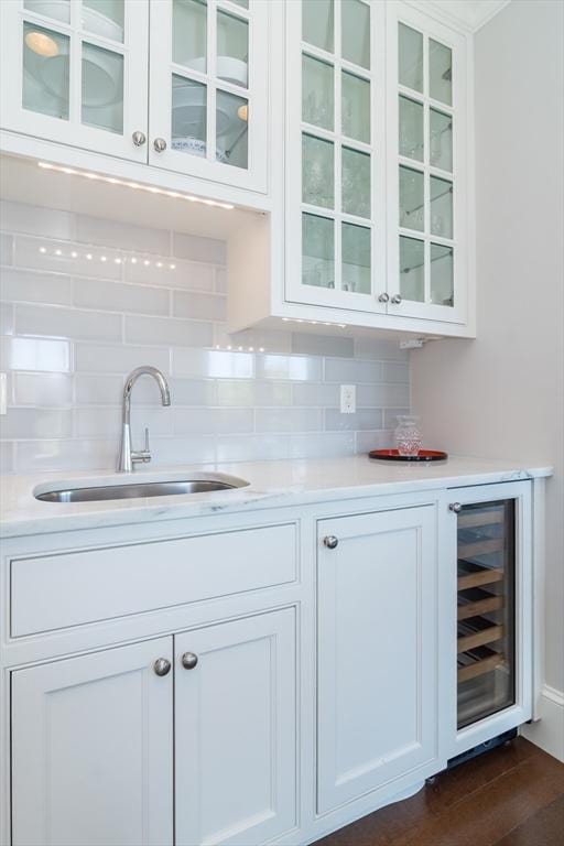 bar with decorative backsplash, sink, white cabinets, and wine cooler