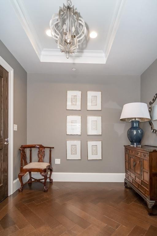 sitting room featuring a tray ceiling, crown molding, dark parquet floors, and an inviting chandelier